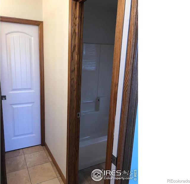 corridor featuring light tile patterned floors and baseboards