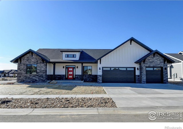 view of front of house with stone siding, board and batten siding, concrete driveway, and a garage