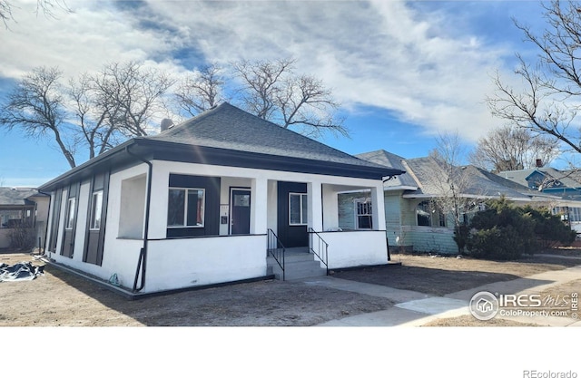 view of front of house featuring stucco siding, covered porch, and a shingled roof