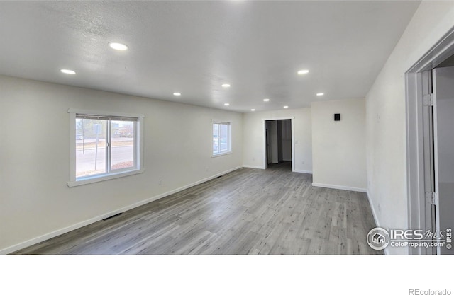 spare room featuring visible vents, recessed lighting, baseboards, and wood finished floors