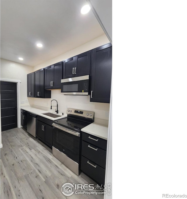 kitchen featuring a sink, light countertops, light wood-style floors, recessed lighting, and stainless steel appliances