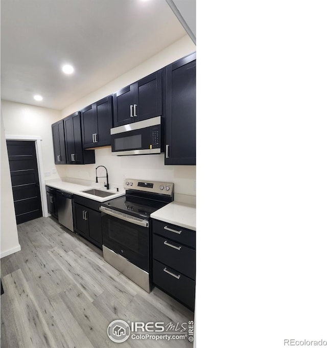 kitchen with recessed lighting, light countertops, light wood-style floors, appliances with stainless steel finishes, and a sink