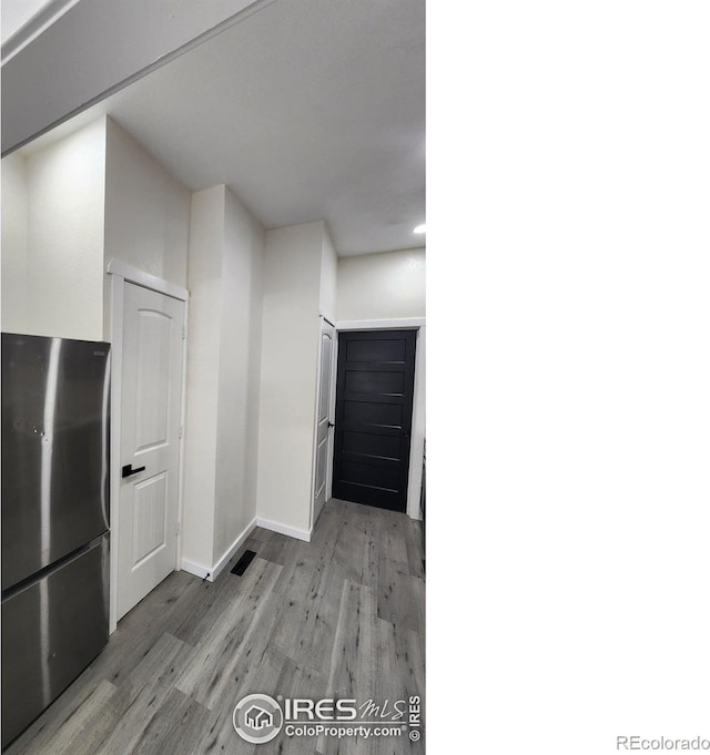 kitchen featuring recessed lighting, light wood-type flooring, freestanding refrigerator, and baseboards