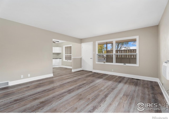 unfurnished living room featuring visible vents, baseboards, and wood finished floors