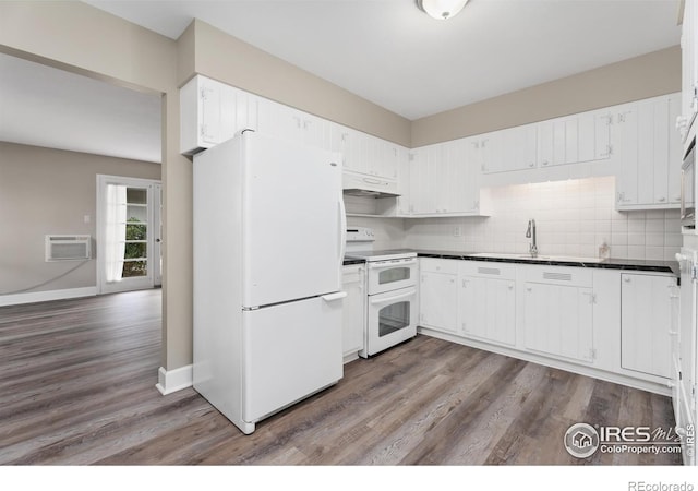 kitchen with a sink, under cabinet range hood, dark countertops, white appliances, and decorative backsplash