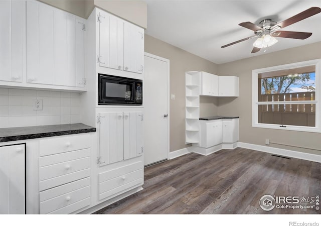 kitchen with dark countertops, white cabinetry, black microwave, decorative backsplash, and dark wood-style flooring