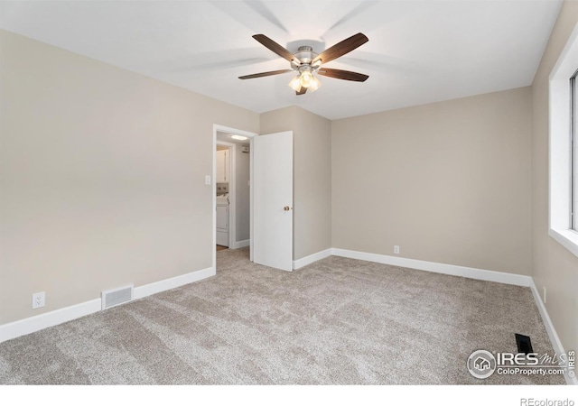 carpeted empty room with visible vents, ceiling fan, and baseboards