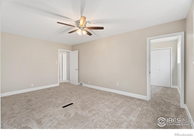 carpeted empty room featuring visible vents, baseboards, and a ceiling fan