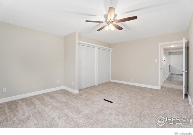 unfurnished bedroom featuring baseboards, carpet flooring, two closets, and visible vents