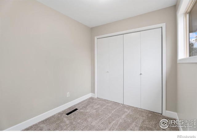 unfurnished bedroom featuring a closet, carpet flooring, baseboards, and visible vents