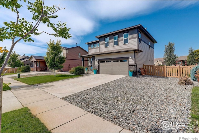 view of front of home with a garage, stone siding, driveway, and fence