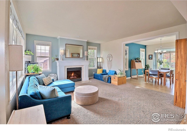 carpeted living area featuring baseboards, a fireplace with flush hearth, plenty of natural light, and an inviting chandelier