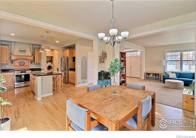 dining area featuring visible vents, an inviting chandelier, washer / clothes dryer, and light wood-style floors