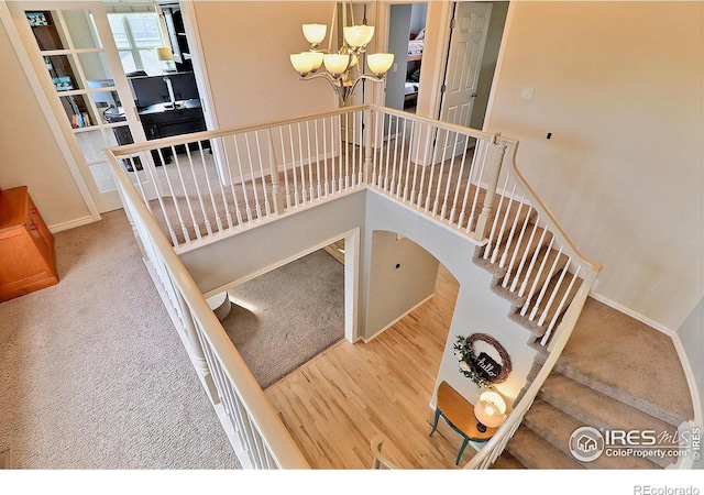 stairs with baseboards, an inviting chandelier, and wood finished floors