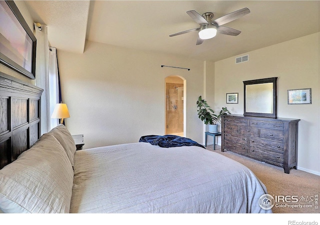 bedroom with visible vents, ensuite bathroom, a ceiling fan, arched walkways, and carpet