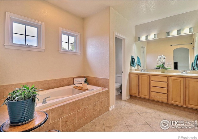 full bathroom featuring a garden tub, toilet, a sink, tile patterned flooring, and double vanity