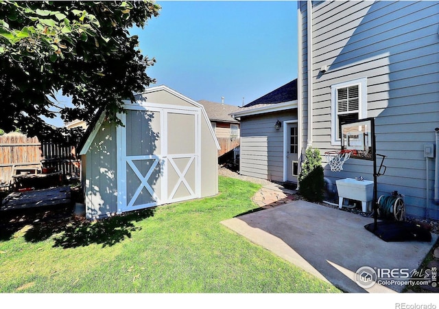 view of yard with a storage shed, fence, an outdoor structure, and a patio area