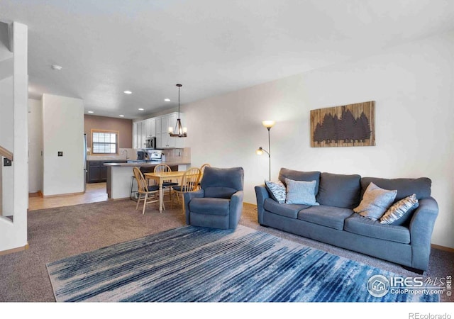 living area featuring a chandelier, recessed lighting, light colored carpet, and baseboards