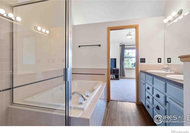 full bath featuring a sink, a relaxing tiled tub, and double vanity