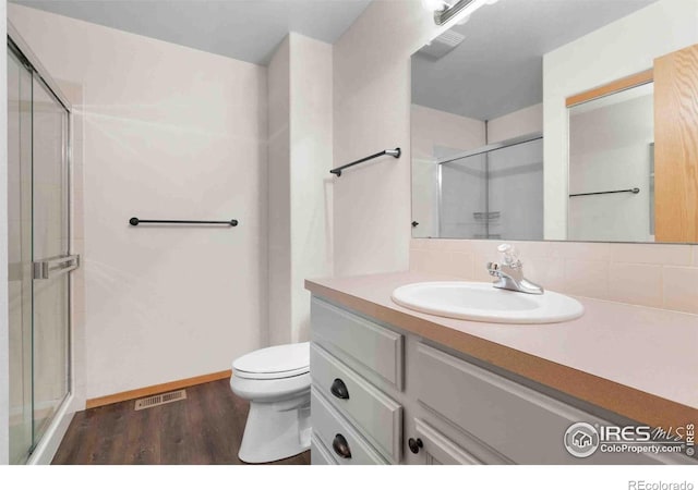 full bathroom with visible vents, a shower stall, toilet, wood finished floors, and vanity