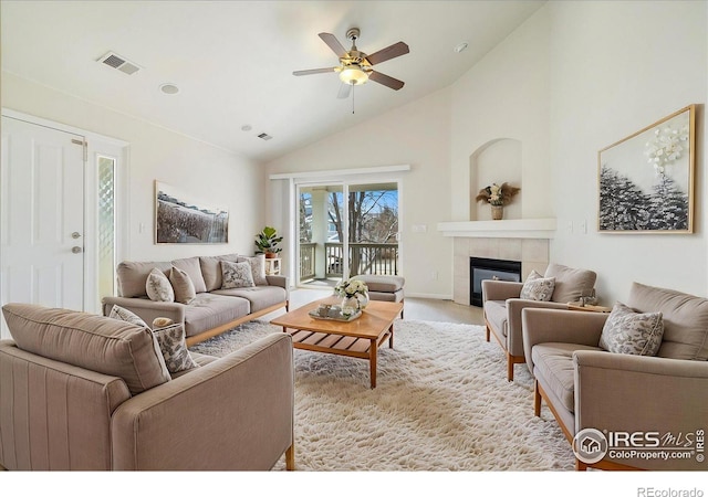 living area with visible vents, a tile fireplace, high vaulted ceiling, and a ceiling fan