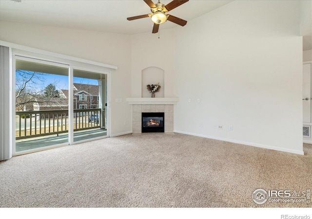 unfurnished living room featuring a tile fireplace, baseboards, carpet, and vaulted ceiling