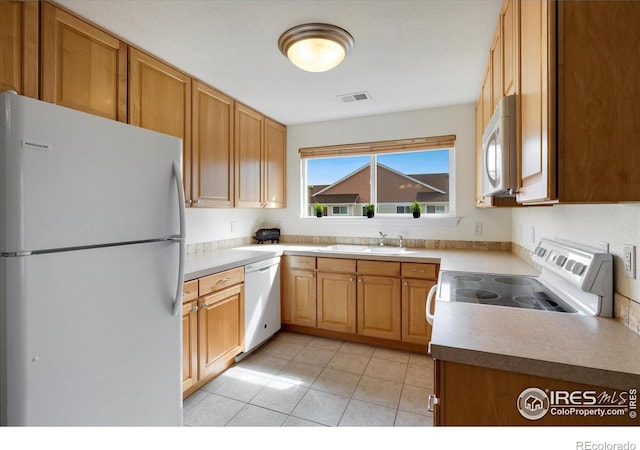 kitchen with white appliances, visible vents, light tile patterned flooring, a sink, and light countertops