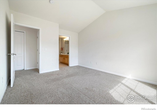 unfurnished bedroom with a sink, ensuite bath, carpet flooring, baseboards, and vaulted ceiling