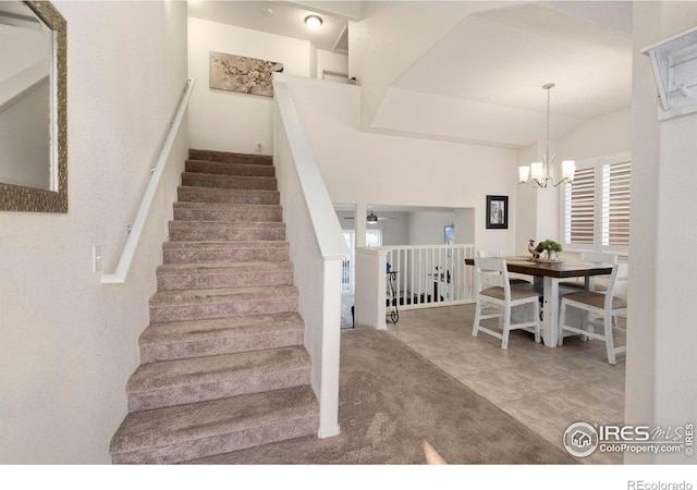 stairway featuring ceiling fan with notable chandelier