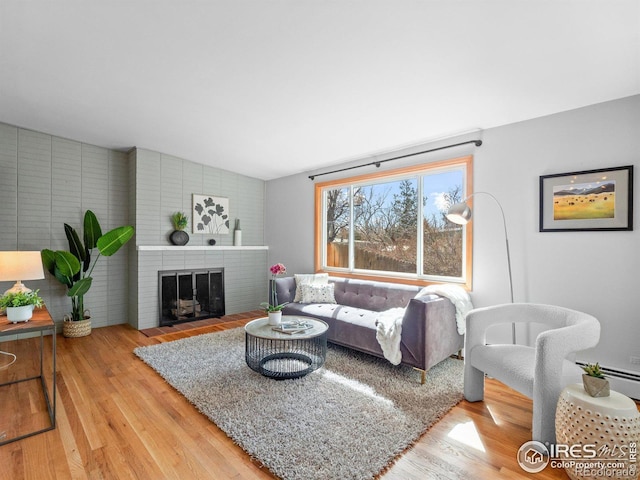 living area with lofted ceiling, a brick fireplace, and wood finished floors