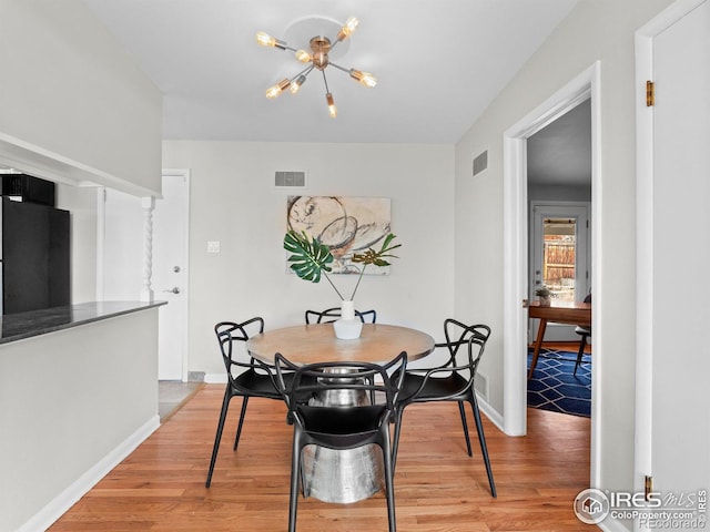 dining room featuring visible vents, a notable chandelier, and light wood-style flooring