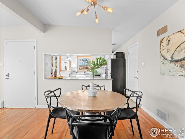 dining room featuring light wood finished floors, visible vents, vaulted ceiling with beams, and baseboards