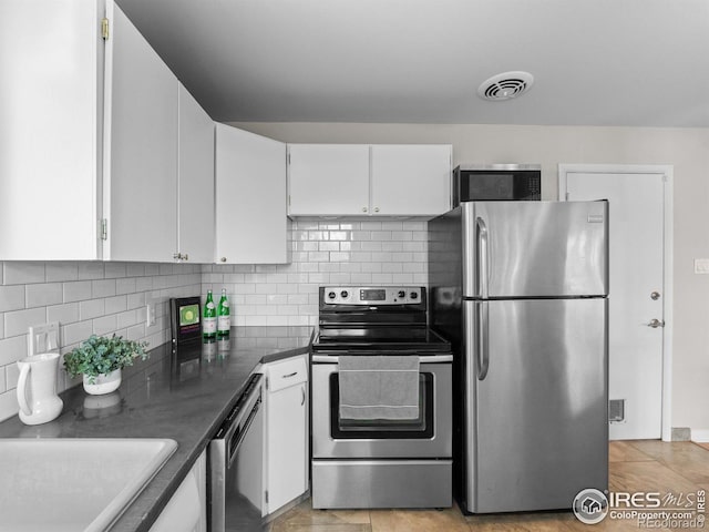 kitchen featuring visible vents, stainless steel appliances, decorative backsplash, white cabinets, and dark countertops