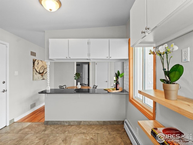 kitchen with visible vents, baseboards, white cabinets, and a baseboard heating unit