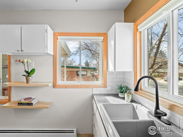 kitchen featuring decorative backsplash, a sink, white cabinetry, a baseboard radiator, and a healthy amount of sunlight