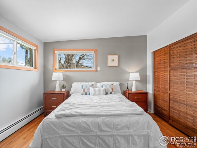 bedroom with wood finished floors and a baseboard radiator