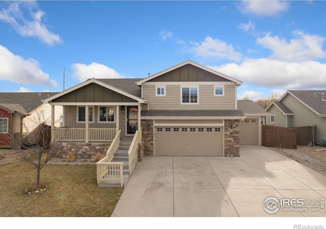 view of front of home featuring board and batten siding, a porch, driveway, stone siding, and an attached garage