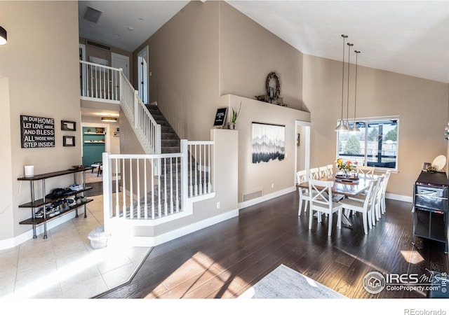 dining area with visible vents, baseboards, high vaulted ceiling, and wood finished floors