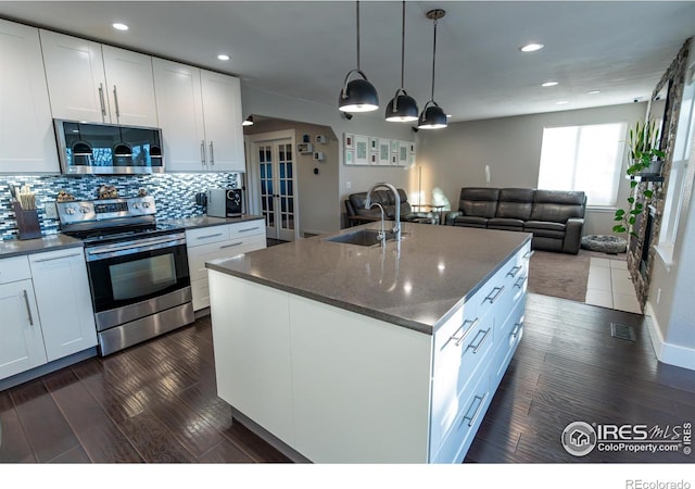 kitchen featuring dark wood finished floors, decorative backsplash, appliances with stainless steel finishes, white cabinetry, and a sink