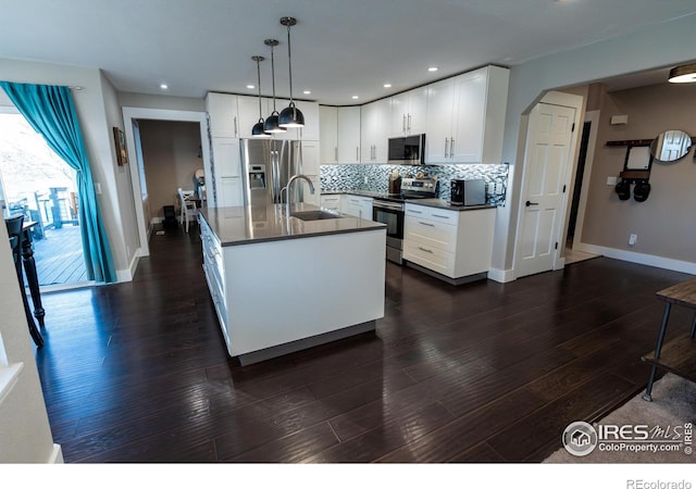 kitchen with dark countertops, backsplash, appliances with stainless steel finishes, arched walkways, and a sink