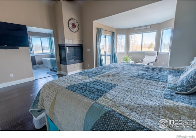 bedroom featuring ensuite bathroom, access to outside, wood finished floors, a fireplace, and baseboards