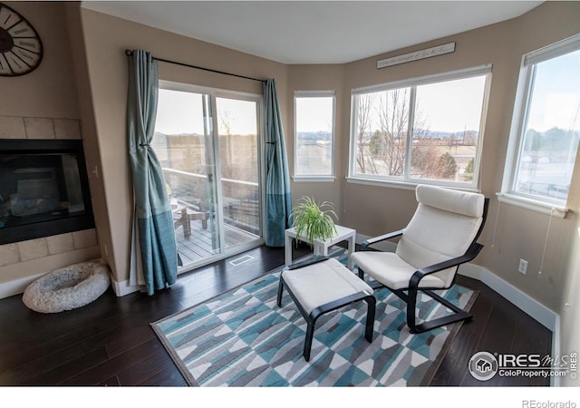 living area featuring a fireplace, dark wood-style floors, and baseboards