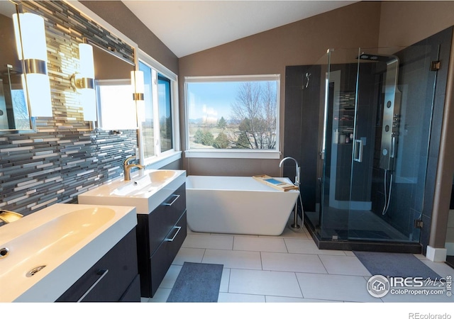 full bath featuring a soaking tub, two vanities, a stall shower, and lofted ceiling