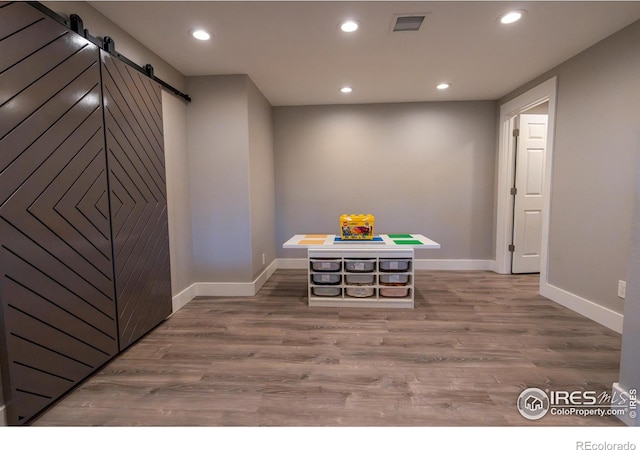 dining area with recessed lighting, a barn door, and wood finished floors