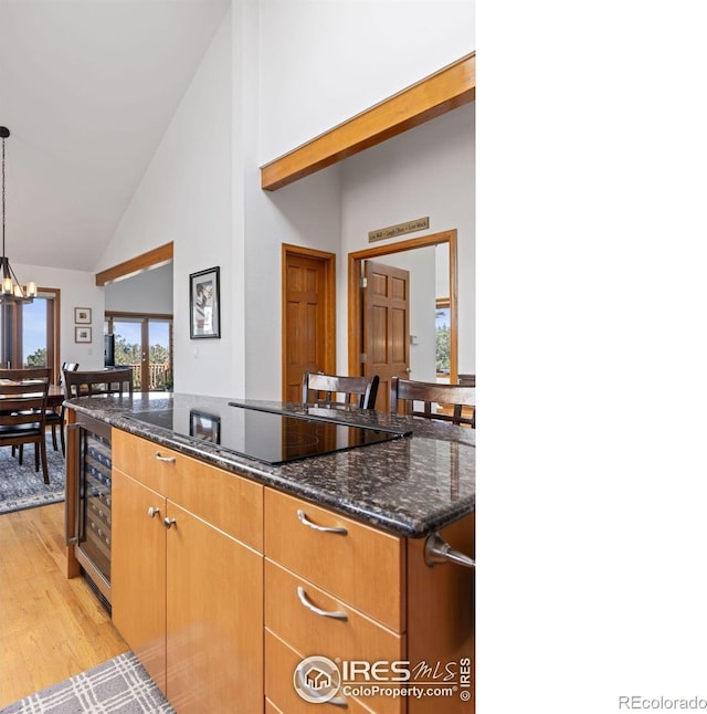 82 Grove Ct, Boulder, CO 80302 - kitchen with beverage cooler, black electric cooktop, light wood-style flooring, high vaulted ceiling, and dark stone countertops