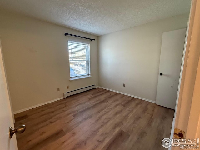 unfurnished room featuring a textured ceiling, wood finished floors, baseboards, and a baseboard radiator