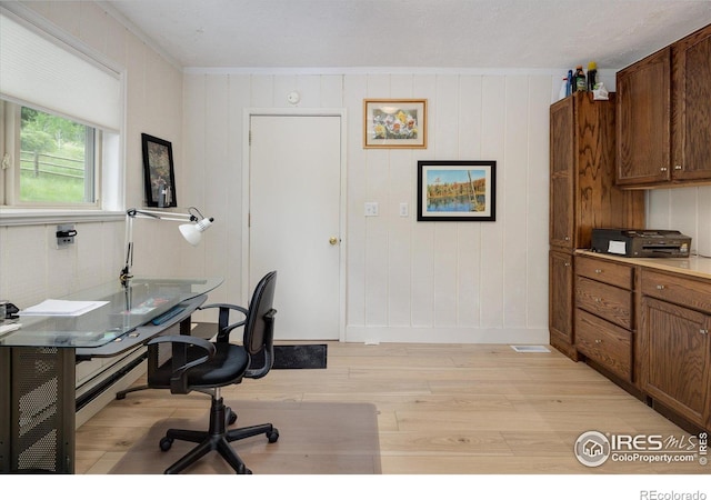 office area featuring baseboards, crown molding, and light wood-style floors