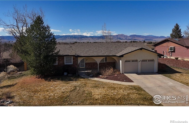 single story home featuring an attached garage, a front lawn, stucco siding, driveway, and a mountain view