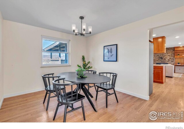 dining room with a chandelier, light wood-type flooring, and baseboards