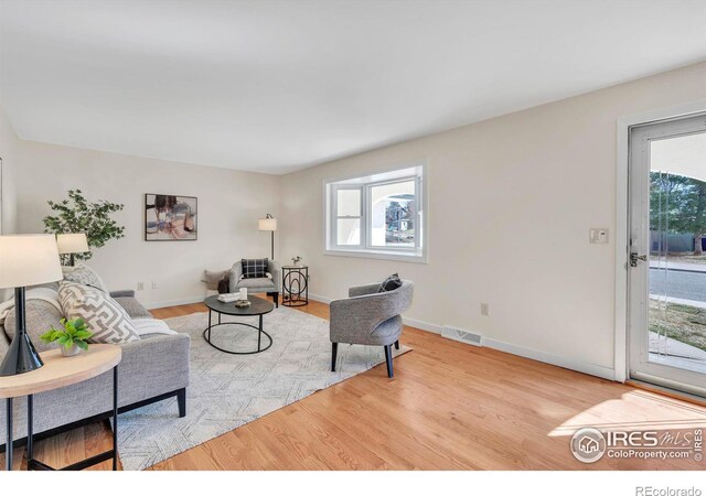 living room with visible vents, baseboards, and wood finished floors